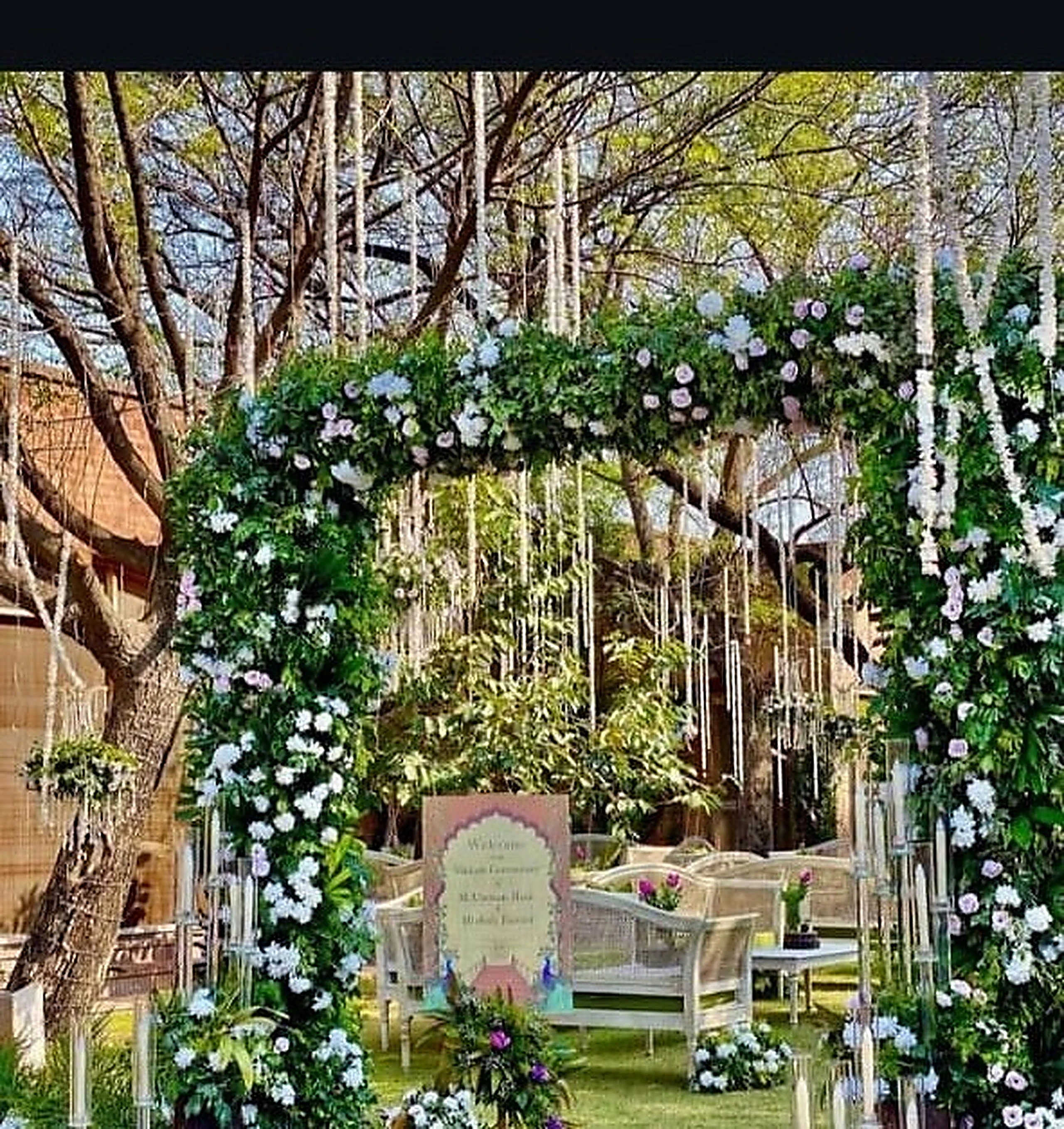 Green floral entrance arch opening onto a lawn celebration