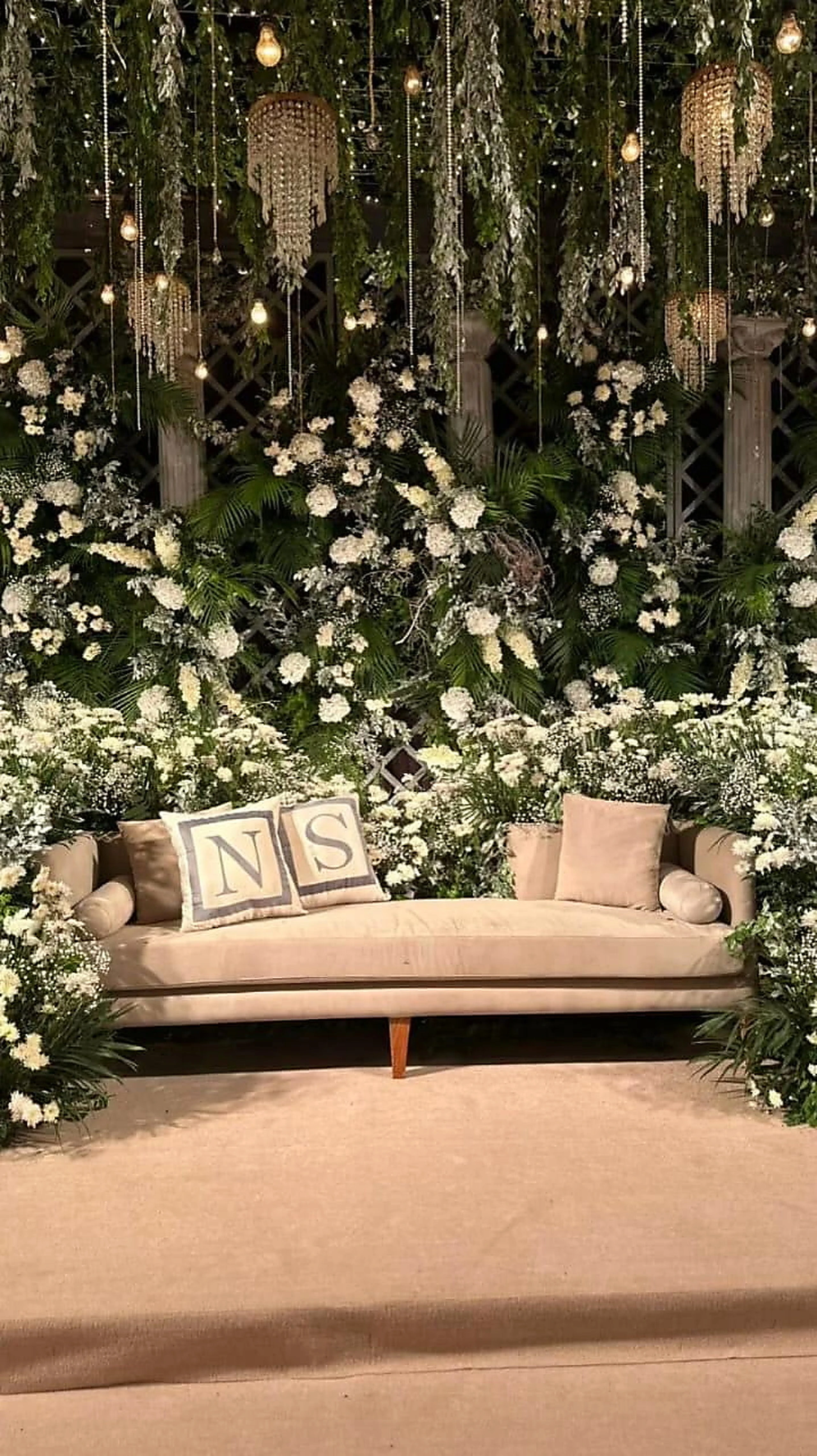 Ivory sofa framed by hanging white blooms and trailing greenery