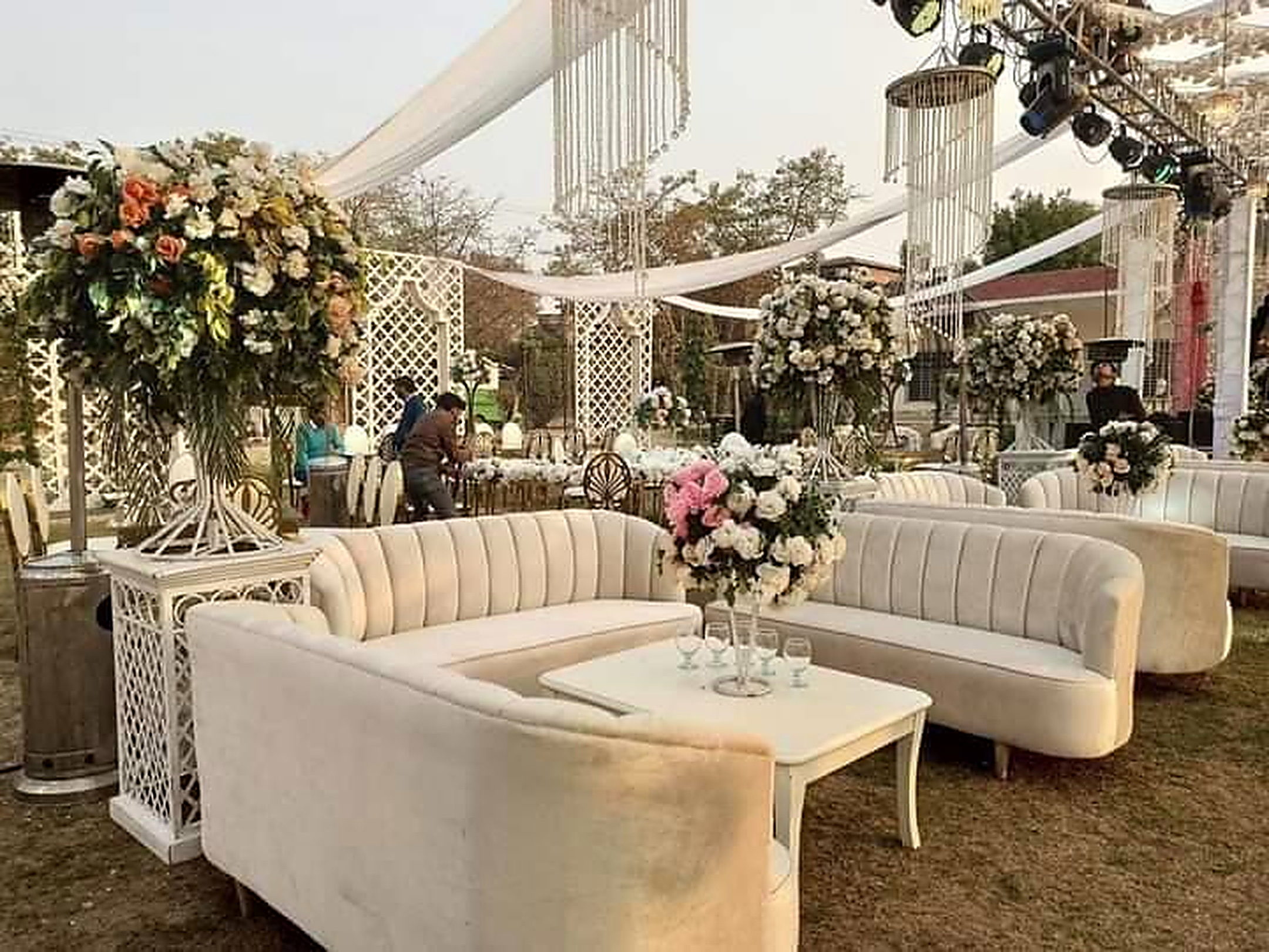 Ivory lounge sofas with marble tables and floral arrangements under a marquee
