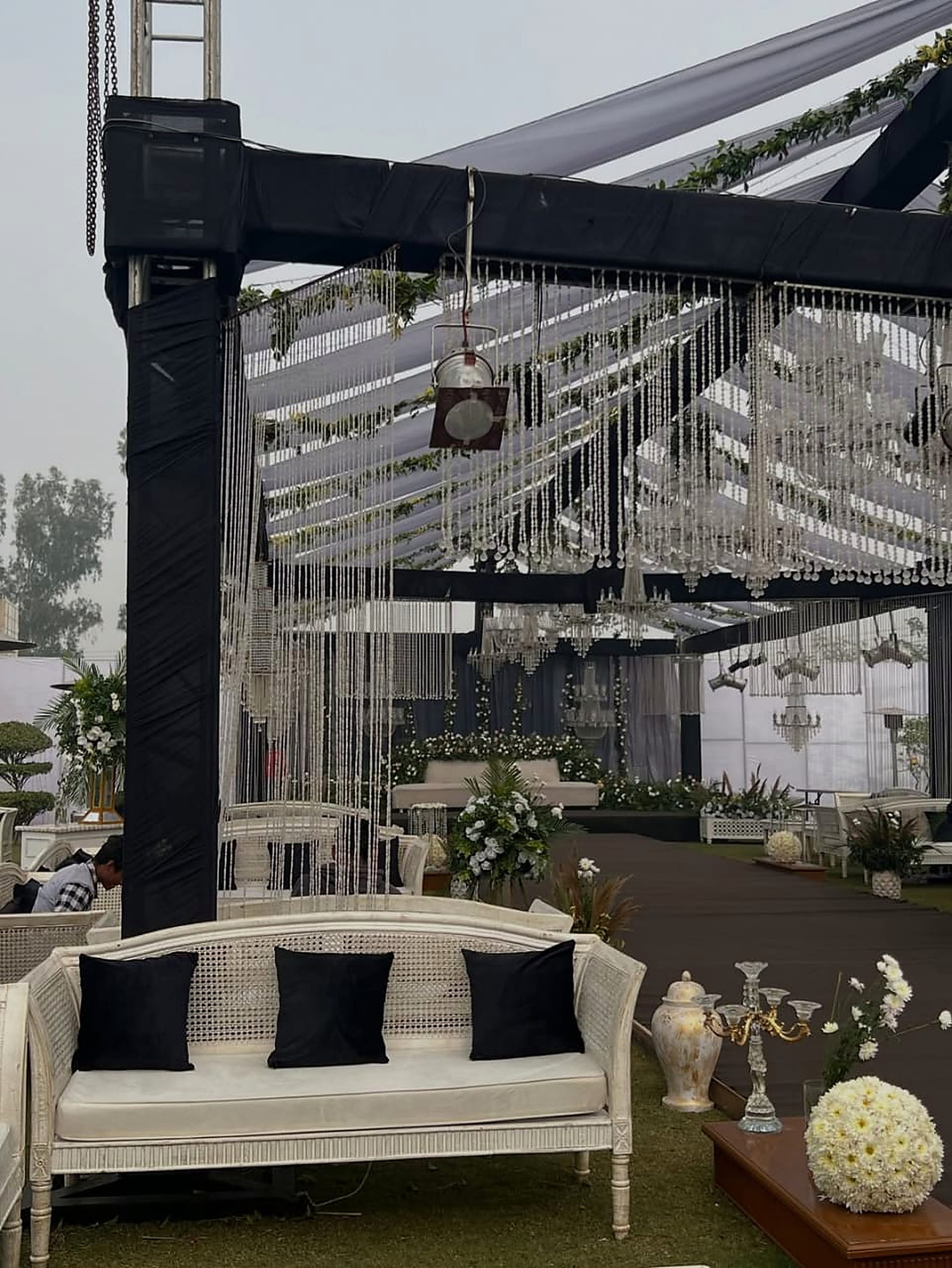 Crystal strand ceiling above a white settee stage inside a covered marquee