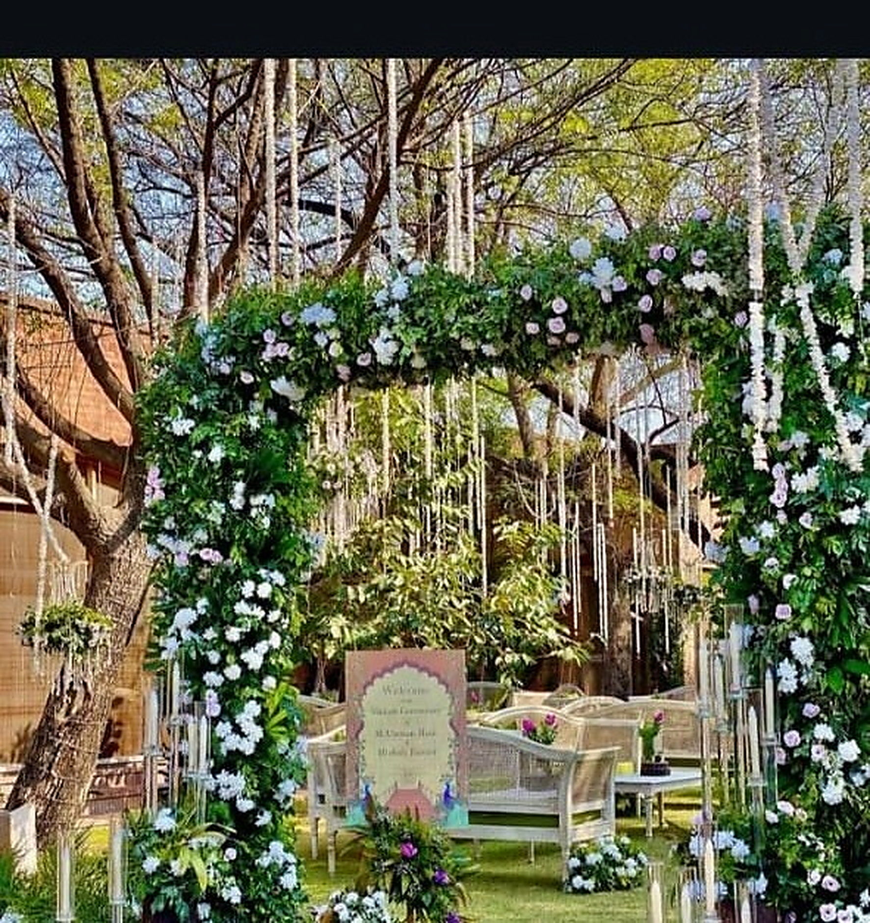 Green floral entrance arch opening onto a lawn celebration
