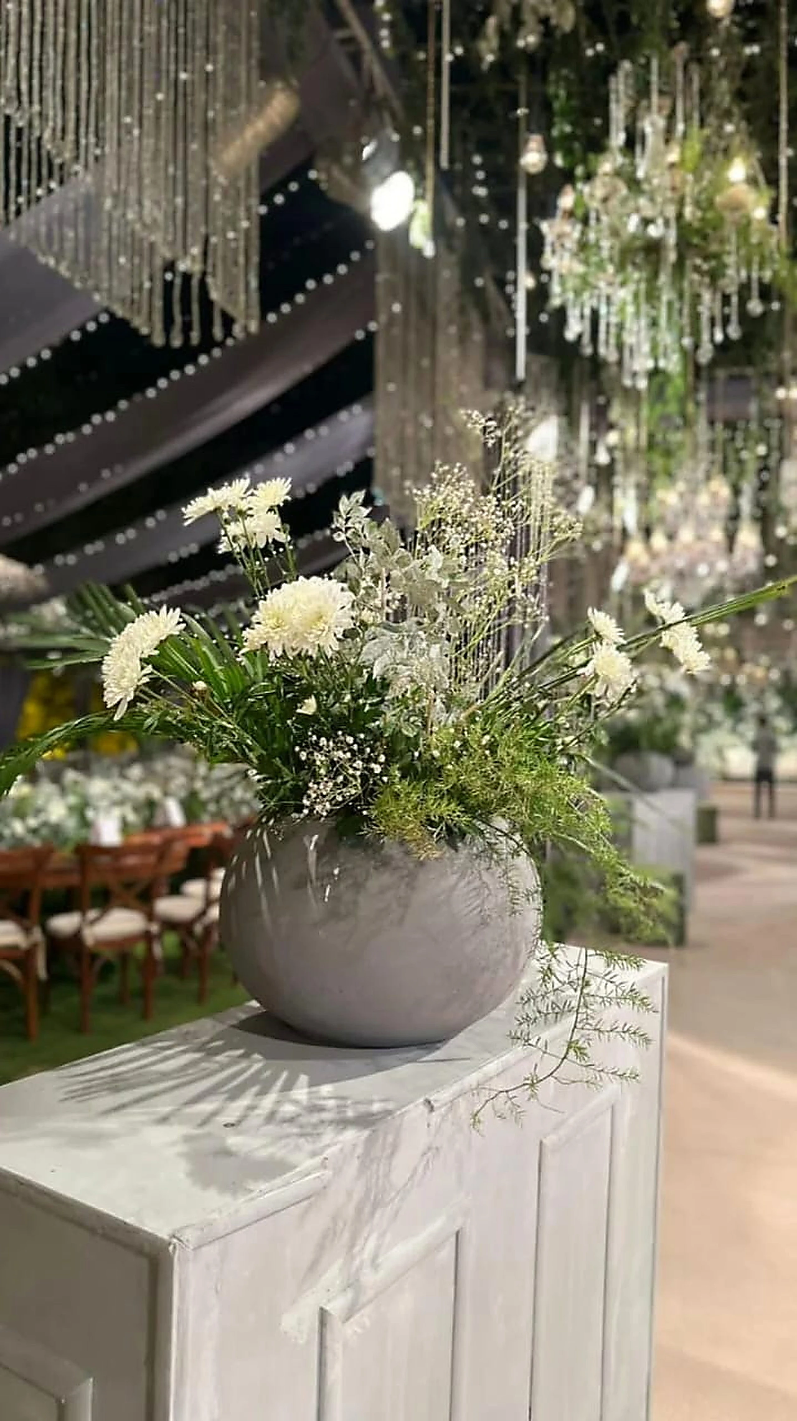 Close study of a white floral urn arrangement beneath crystal drops
