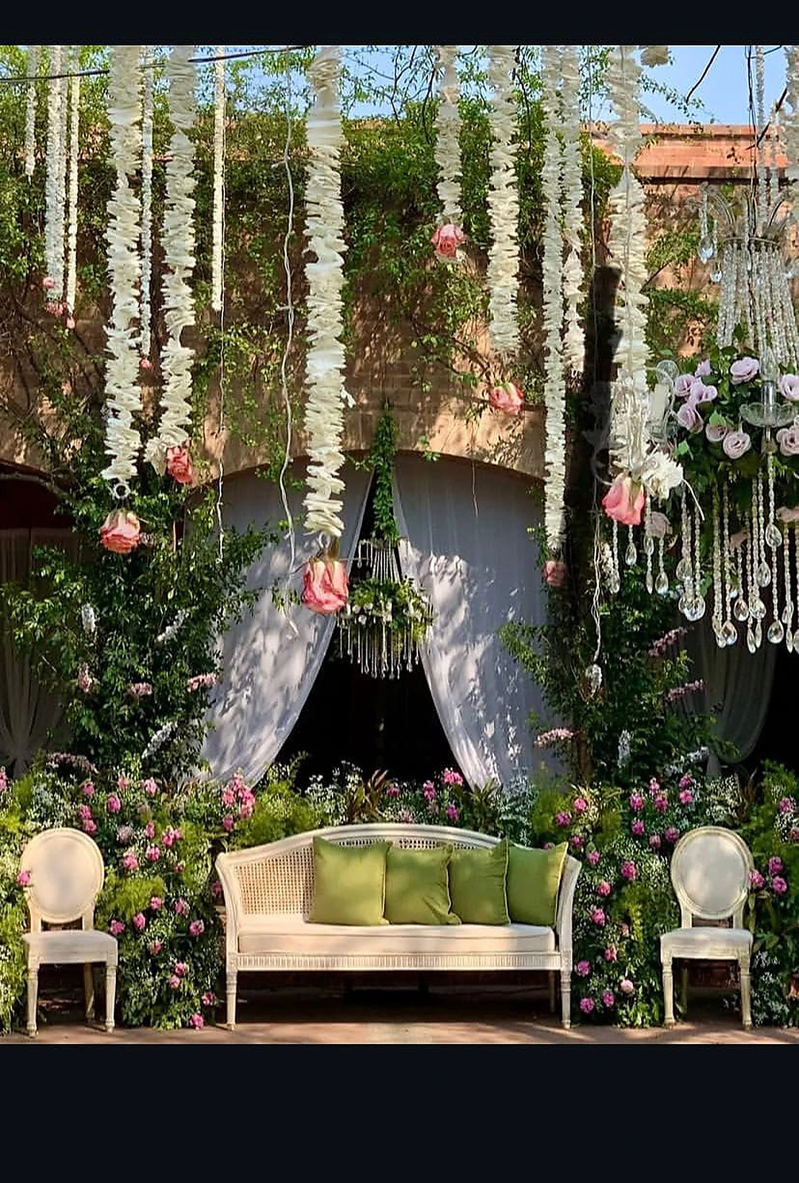 Sage and blush stage with draped fabric, florals and carved chairs
