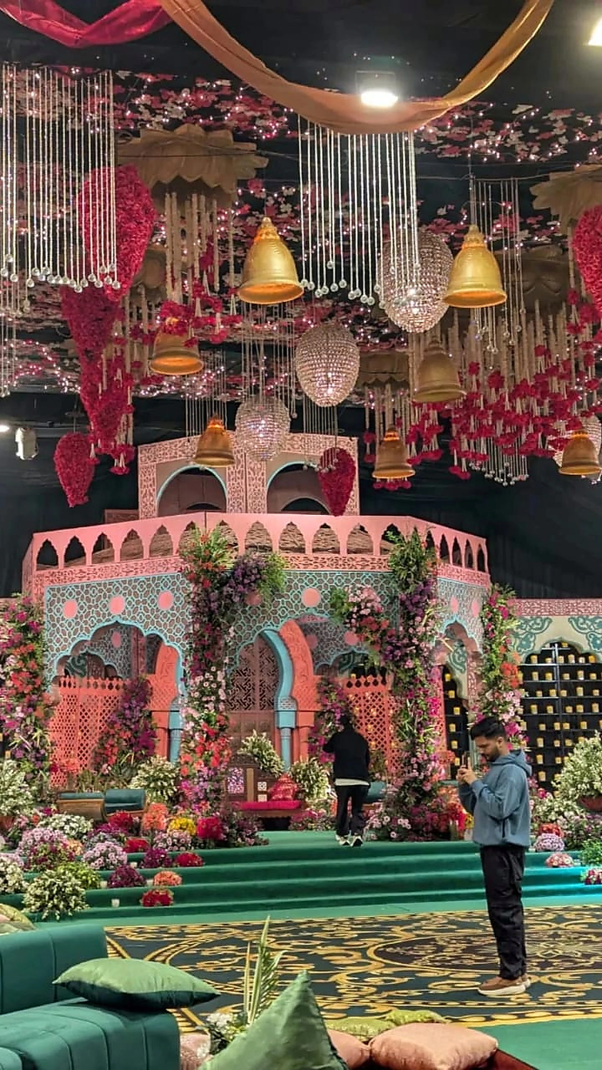 Colourful mehndi stage with jharoka arches, marigolds and floor seating