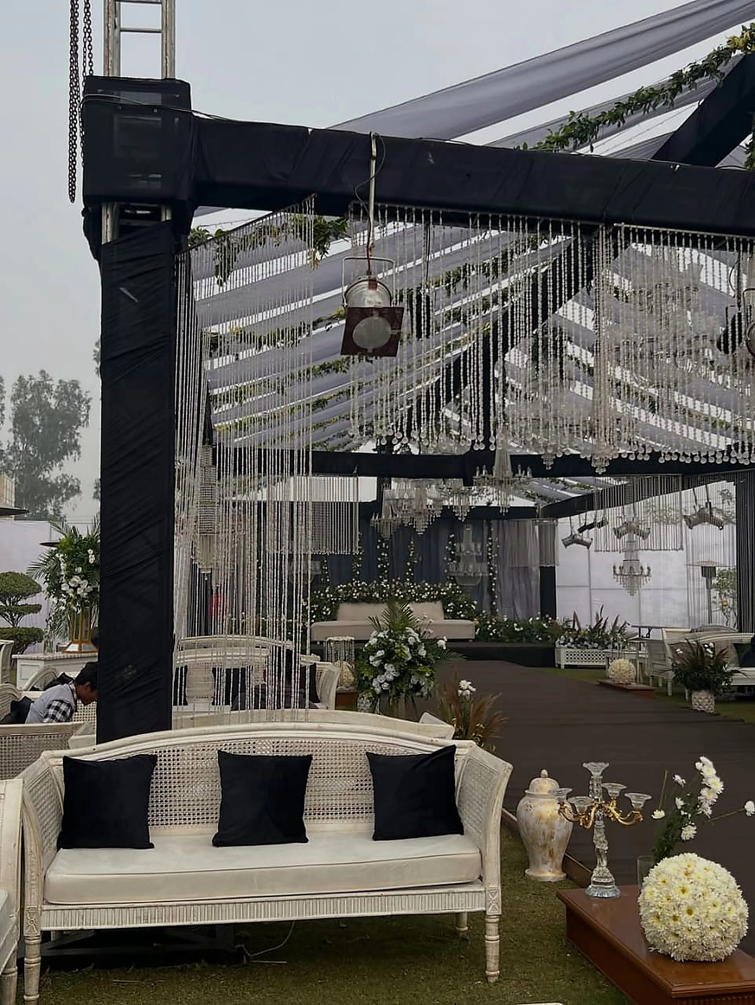 Crystal strand ceiling above a white settee stage inside a covered marquee