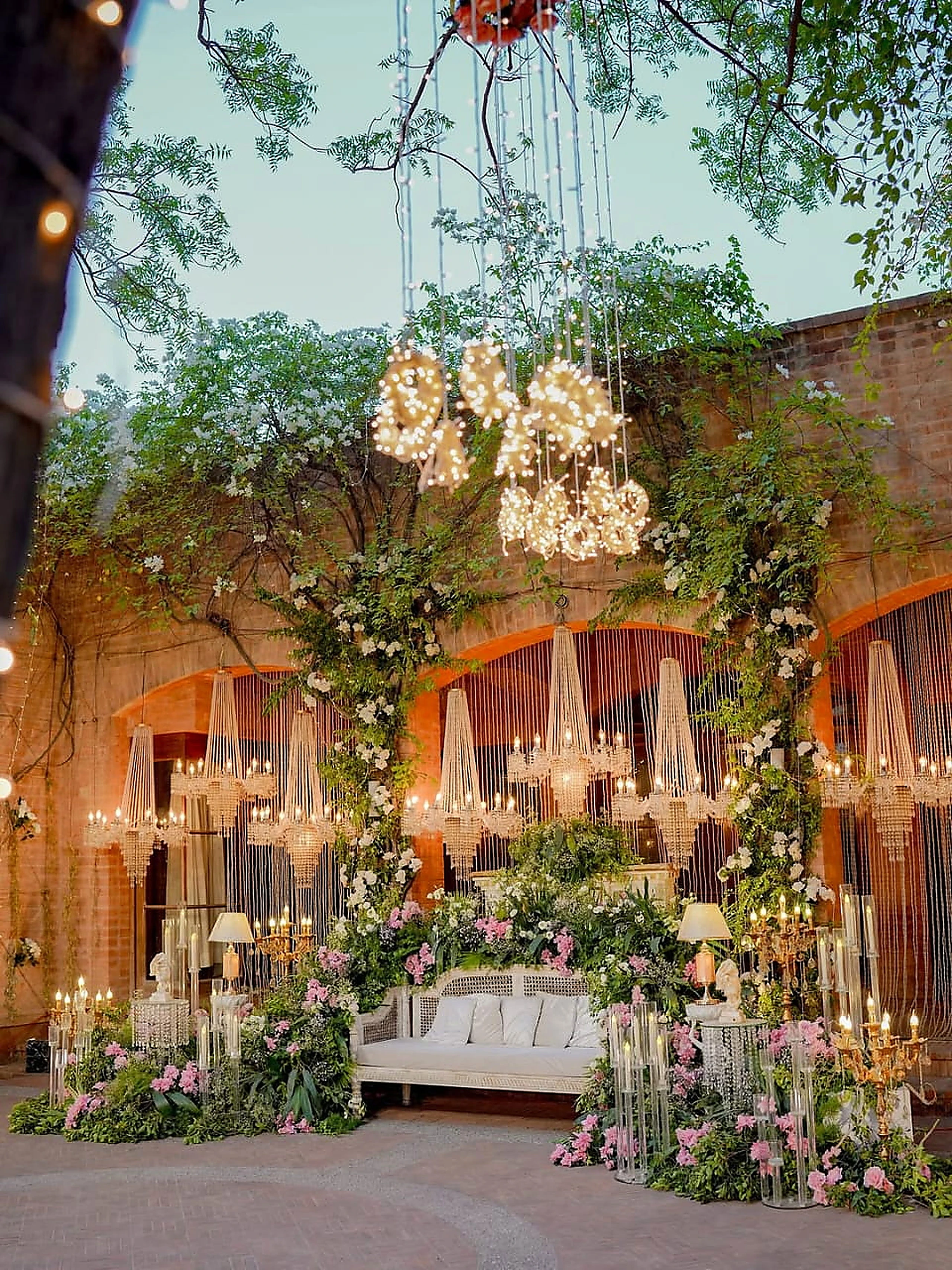Floral wedding stage with hanging blossoms and candlelit console tables at a Lahore farmhouse