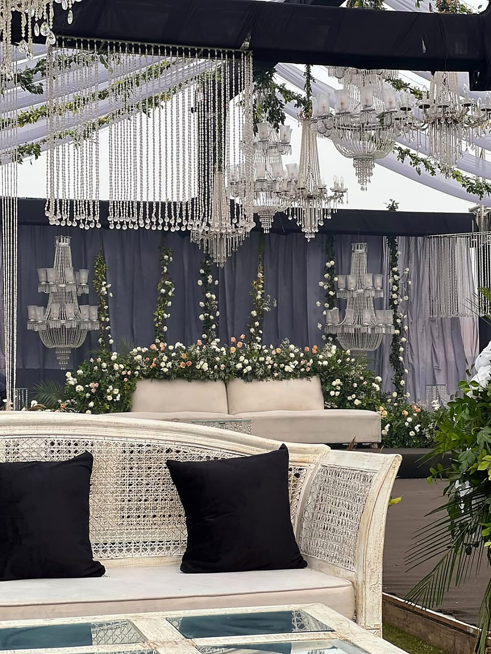 Cane and white upholstered lounge seating with black cushions under crystal drops