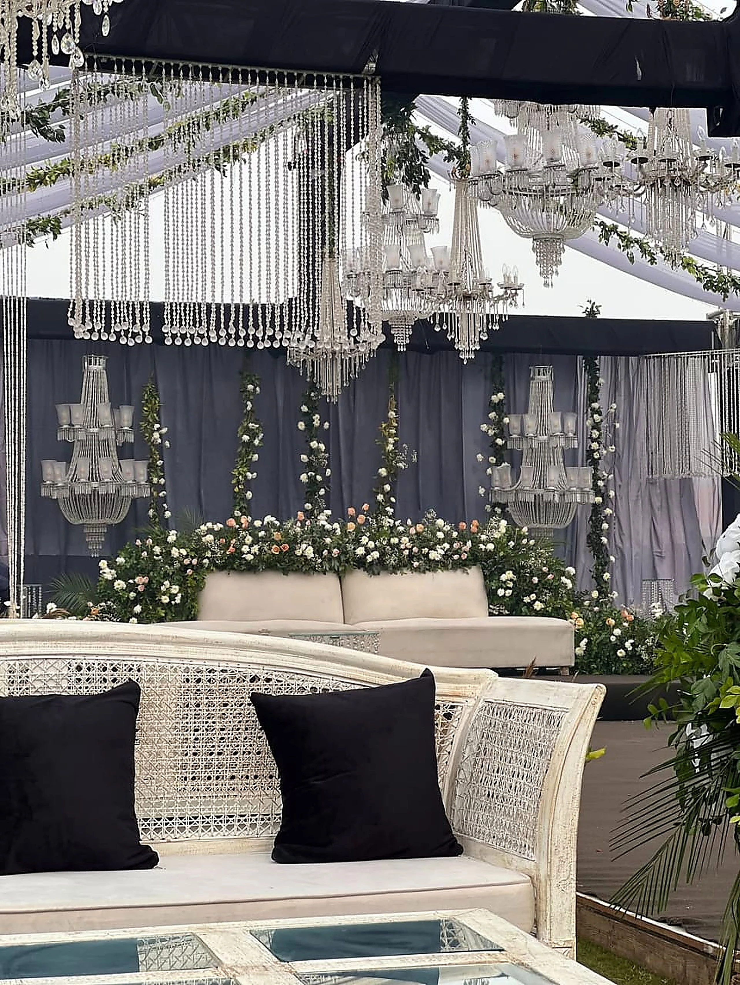 Cane and white upholstered lounge seating with black cushions under crystal drops